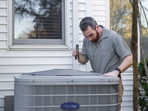 Technician inspecting an outdoor HVAC unit